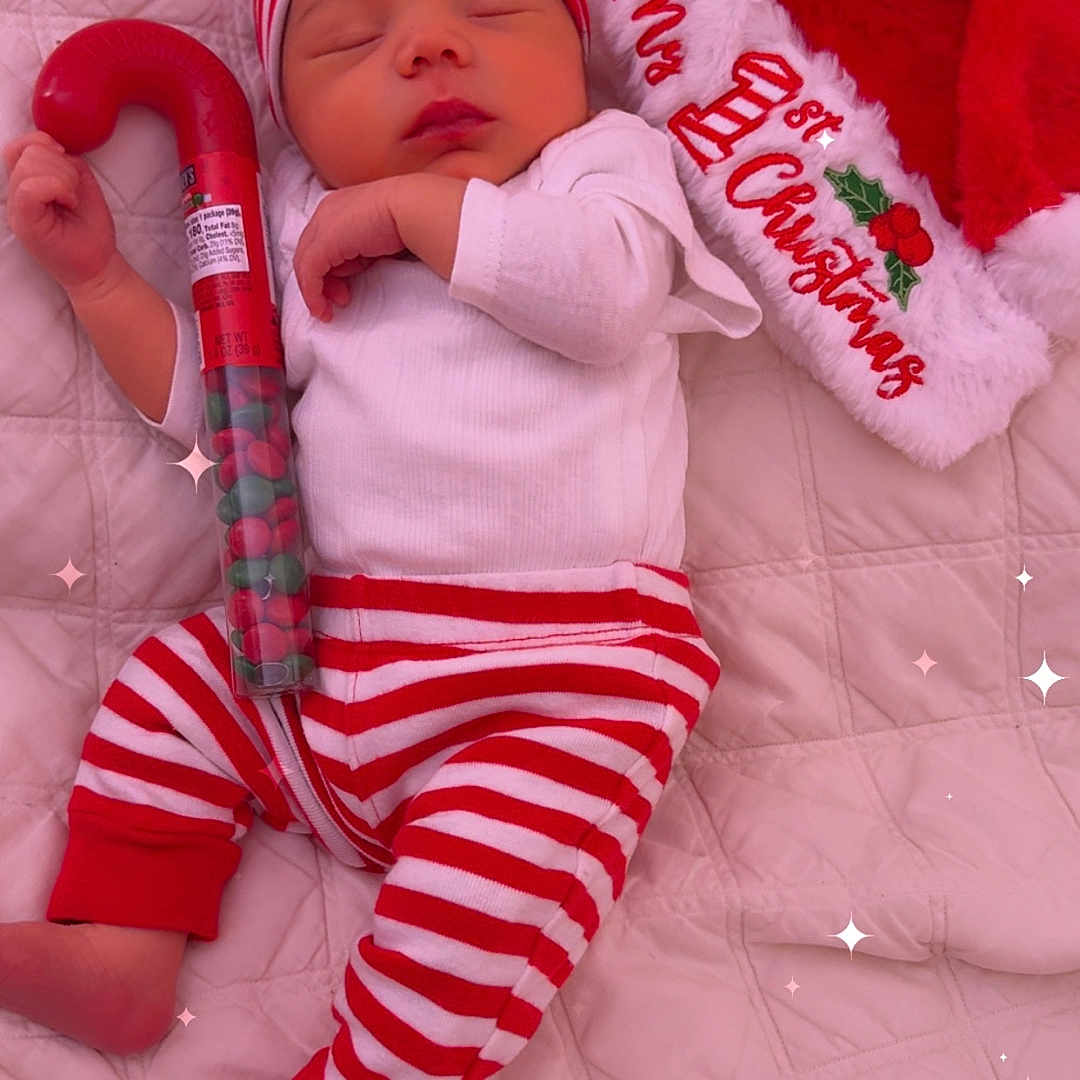 Iñaki is registered to the contest to win money with this photo: baby, bed, candy, candy_cane, celebration, christmas, cozy, cute, festive, hat, holiday, infant, pajamas, peaceful, quilted_blanket, red_and_white, santa_hat, sleeping, sparkles, striped_clothing