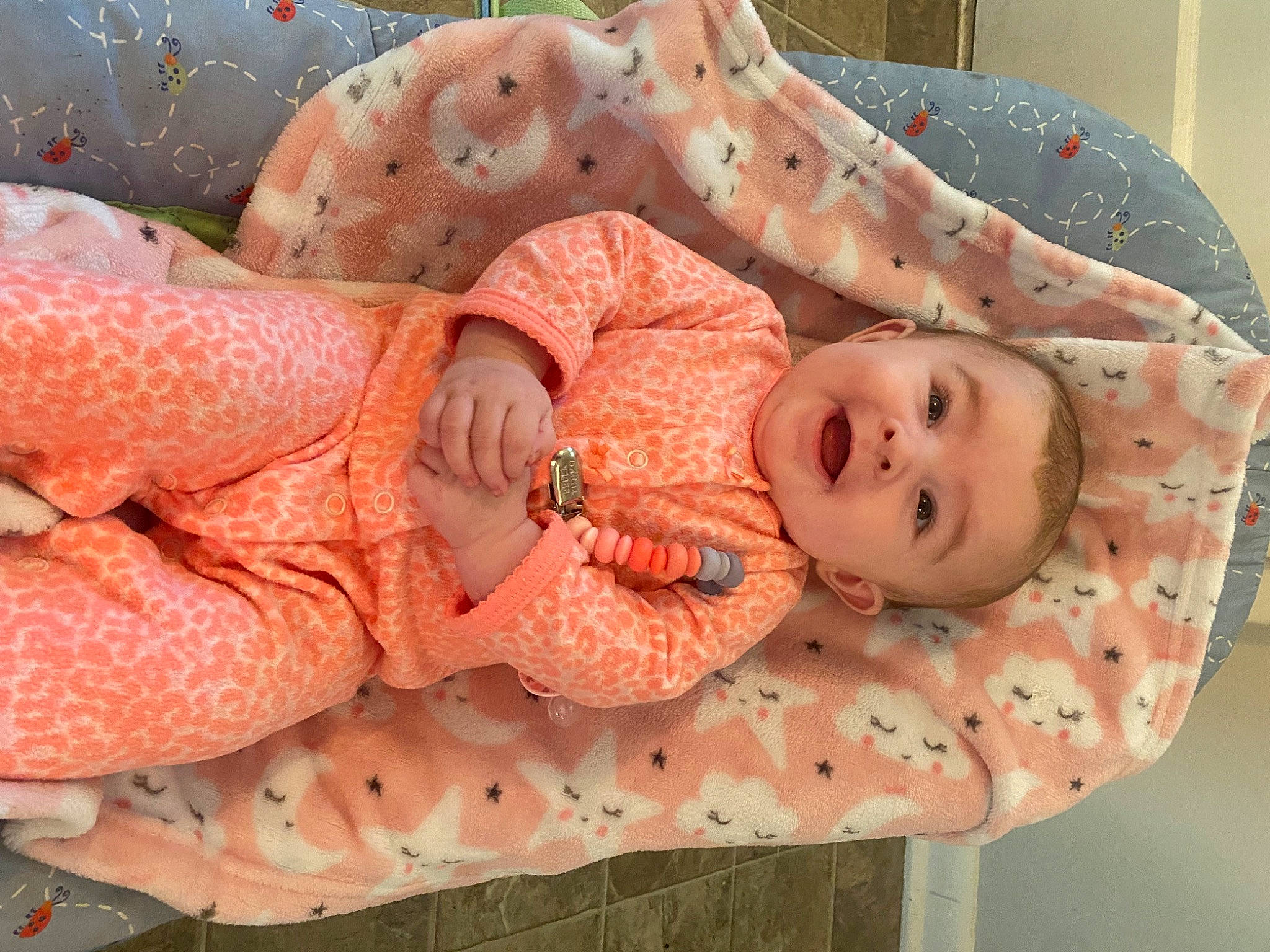 Rosalyn is registered to the contest to win money with this photo: baby, baby_products, baby_safety, baby_toddler_clothing, cheek, child, comfort, eye, face, head, linens, mouth, orange, pattern, peach, person, pink, skin, smile, textile