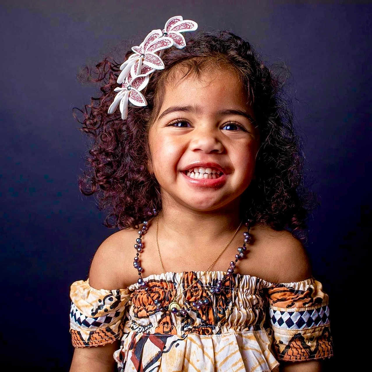 Lourdes a rejoint le concours — aidez-le/la à gagner de superbes lots ! accessories, baby, babylaughing, blackhair, child, clothing, dress, face, female, girl, hair, happy, head, jewelry, laughing, necklace, person, photography, portrait, smile