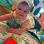 baby, baby_girl, child, clothing, colorful, cute, face, hand, happy, headband, indoor, infant, lying_down, panda_toy, play_mat, playtime, smile, star_toy, stuffed_toy, toy