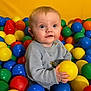 baby, child, playing, ball_pit, colorful, plastic_balls, yellow, blue, red, green, orange, sweater, indoor, cute, smiling, happy, portrait, young, fun, play