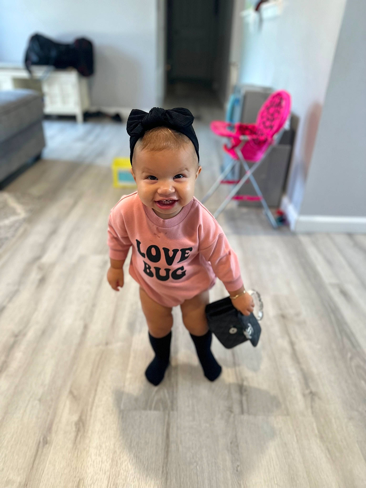 Eliana Rose joined the competition — help win amazing prizes! baby, baby_toddler_clothing, chair, child, face, floor, flooring, happy, hardwood, head, headgear, human_leg, joy, knee, person, sitting, skin, sleeve, smile, t_shirt