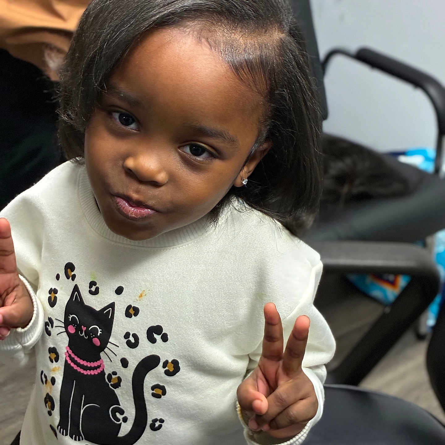 Lamiyah joined the competition — help win amazing prizes! child, girl, peace_sign, sweater, cat_design, leopard_print, indoor, chair, black_hair, smile, cute, casual, portrait, person, fashion, confident, young, playful, happy, cozy
