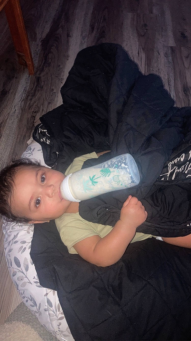 Jaylani joined the competition — help win amazing prizes! arm, baby, baby_products, baby_toddler_clothing, bottle, child, comfort, drinkware, elbow, electric_blue, hand, human_leg, knee, nail, person, plastic_bottle, sitting, thigh, toddler, water_bottle