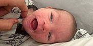 Kenan is registered to the contest to win money with this photo: baby, bed, closeup, clothing, cute, expression, face, hand, happy, indoors, infant, lying_down, newborn, person, pillow, portrait, skin, sleepwear, smiling, soft