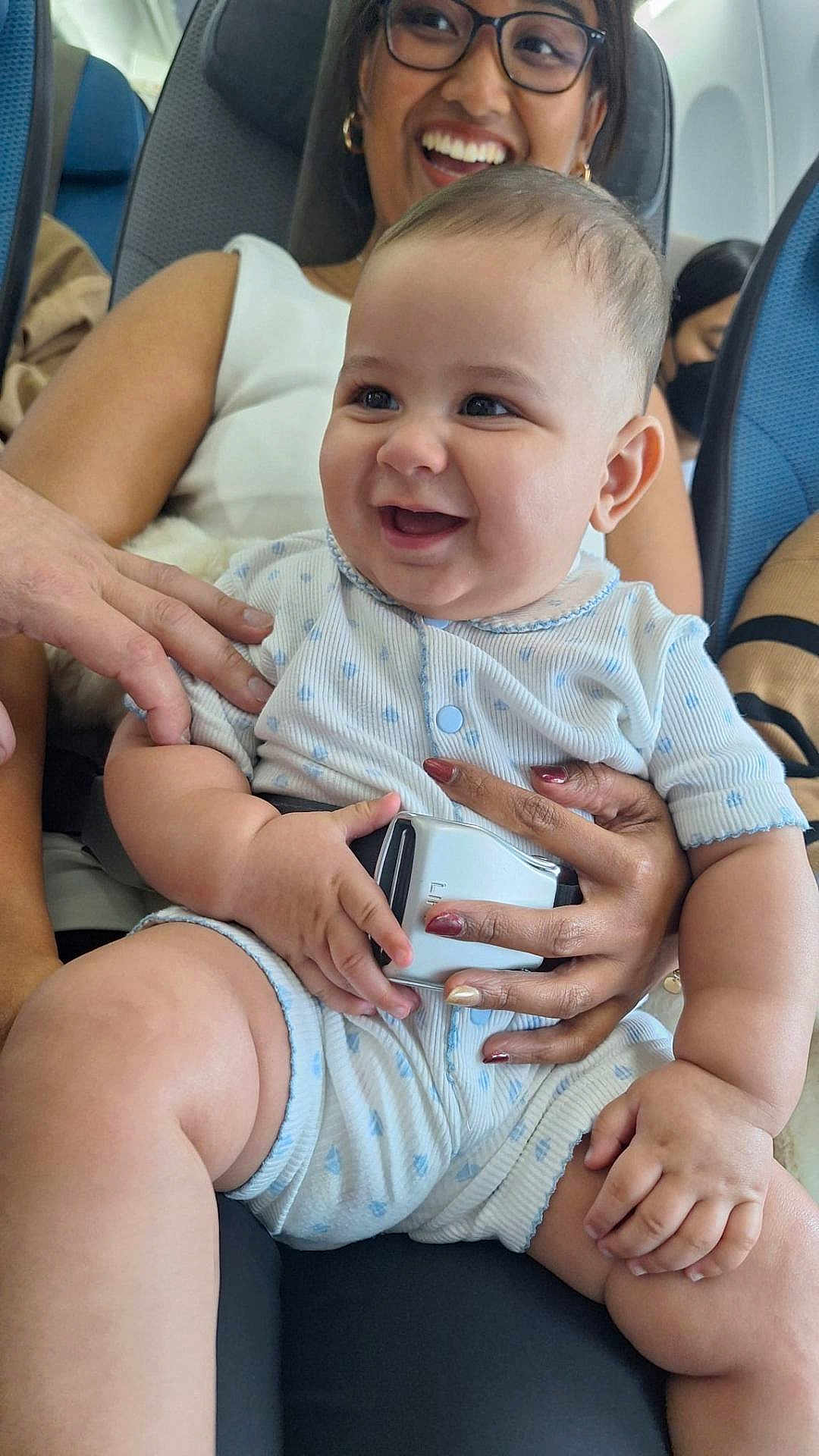 Alexandre Grangier participe au concours pour gagner de l'argent avec cette photo : baby, adult, smile, seat, airplane, seatbelt, clothing, hand, woman, glasses, happy, travel, child, holding, people, portrait, casual, indoor, cute, family