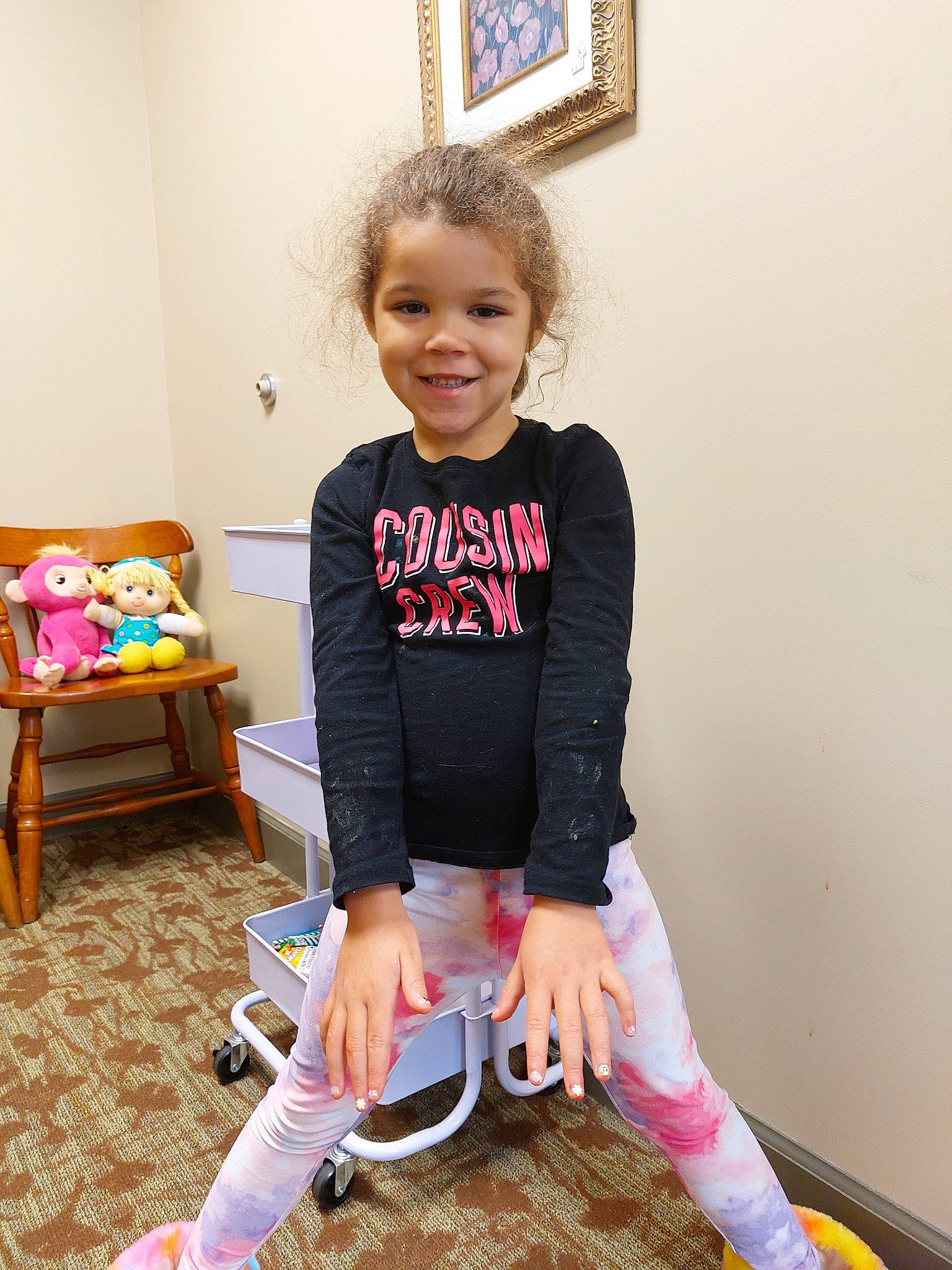 Alyssa is registered to the contest to win money with this photo: baby_toddler_clothing, chair, child, flooring, fun, happy, human_body, human_leg, joy, knee, pattern, person, picture_frame, play, sitting, sleeve, smile, sock, standing, t_shirt