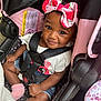 baby, bow, car_seat, child, clothing, cute, denim_shorts, face, hair, headband, indoors, infant, person, pink, safety, seatbelt, skin, smile, sock, straps