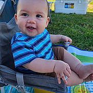 Jax joined the competition — help win amazing prizes! baby, child, smiling, blue_shirt, striped_shirt, outdoor, grass, chair, play_mat, happy, face, person, cute, summer, daylight, nature, legs, hand, seat, infant
