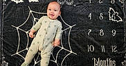 Jax is registered to the contest to win money with this photo: baby, bat, black_background, butterfly, child, cute, decor, floor, happy, indoors, infant, lying_down, milestone_blanket, months, pajamas, portrait, smile, spiderweb, white_design, young