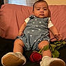 baby, infant, romper, blue_clothing, heart_pattern, white_booties, red_rose, couch, pink_pillow, black_fabric, indoor, child, person, portrait, seated, cute, expression, furniture, skin, head