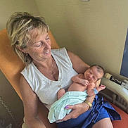 Victory participe au concours pour gagner de l'argent avec cette photo : woman, newborn, baby, smiling, indoor, chair, blanket, happy, holding, person, skin, furniture, relaxed, short_hair, casual_clothing, watch, nail_polish, radiator, home, portrait