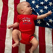 Sebastian joined the competition — help win amazing prizes! baby, infant, onesie, red_clothing, american_flag, stars, stripes, lying_down, cute, child, newborn, patriotic, holiday, celebration, skin, person, small_child, indoor, fabric, background