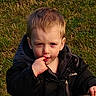 Ethan is registered to the contest to win money with this photo: child, toddler, boy, portrait, outdoor, grass, sitting, lollipop, candy, eating, black_jacket, blond_hair, face, eyes, hand, playground, warm_light, closeup, innocent, photography