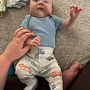 Jude is registered to the contest to win money with this photo: baby, infant, hand, clothing, pants, shirt, blanket, diapers, foot, person, playful, cute, car_prints, soft_texture, lying_down, indoor, family, toddler, hand_holding, curious_expression