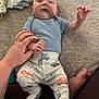 baby, infant, hand, clothing, pants, shirt, blanket, diapers, foot, person, playful, cute, car_prints, soft_texture, lying_down, indoor, family, toddler, hand_holding, curious_expression