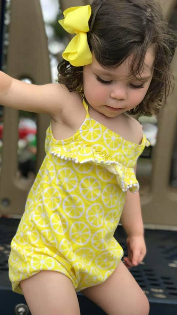 Braylee is registered to the contest to win money with this photo: abdomen, baby, child, child_model, clothing, design, dress, pattern, person, play, polka_dot, ruffle, smile, swimwear, textile, toddler, yellow