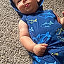 baby, child, infant, blue_clothing, hoodie, shark_print, carpet, tongue_out, playful, cute, chubby_cheeks, lying_down, casual, indoor, person, small_hand, headwear, comfortable, relaxed, young