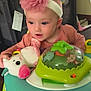 baby, infant, headband, pink_flower, stuffed_toy, unicorn, baby_walker, toy, indoor, child, cute, playtime, face, person, clothing, seat, furniture, happy, curious, home