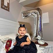 Georgina joined the competition — help win amazing prizes! baby, balloon, bed, black_dress, bouquet, bow_headband, cake, celebration, child, cute, flower, footwear, happy, headband, indoors, number_one, pillow, portrait, red_roses, smiling