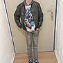 Ethan participe au concours pour gagner de l'argent avec cette photo : boy, casual, child, clothing, door, fashion, floor, graphic_print, hallway, hands_in_pockets, hoodie, indoor, jeans, leather_jacket, person, portrait, pose, sneakers, standing, young