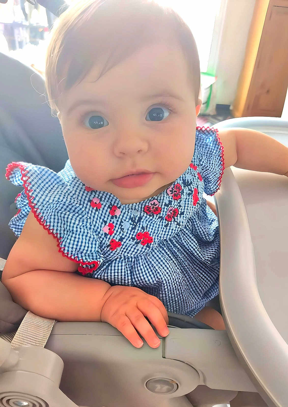 Aloïs participe au concours pour gagner de l'argent avec cette photo : baby, child, high_chair, blue_dress, floral_pattern, curious, face, hand, indoor, natural_light, soft_light, cute, infant, portrait, seat, expression, young_child, person, closeup, skin