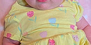 Ella is registered to the contest to win money with this photo: baby, infant, yellow_dress, headband, flower, pink_blanket, hearts, cute, child, portrait, smiling, soft_texture, indoor, closeup, skin, person, happy, toddler, lying_down, apparel