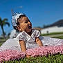 Hannah joined the competition — help win amazing prizes! baby, child, smiling, dress, tiara, grass, outdoor, blue_sky, happy, pink_rug, cute, portrait, headband, sunny, infant, laughing, celebration, nature, daylight, young