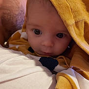 Arthur a rejoint le concours — aidez-le/la à gagner de superbes lots ! baby, infant, child, blanket, hood, face, person, adult, closeup, curious, wide_eyes, warm_lighting, soft_texture, indoor, portrait, cozy, yellow, white, clothing, family