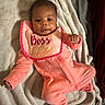 baby, infant, pink_clothing, bib, smiling, lying_down, blanket, cozy, cute, child, portrait, soft_texture, home, comfortable, young_child, raised_fist, face, head, person, sleepwear