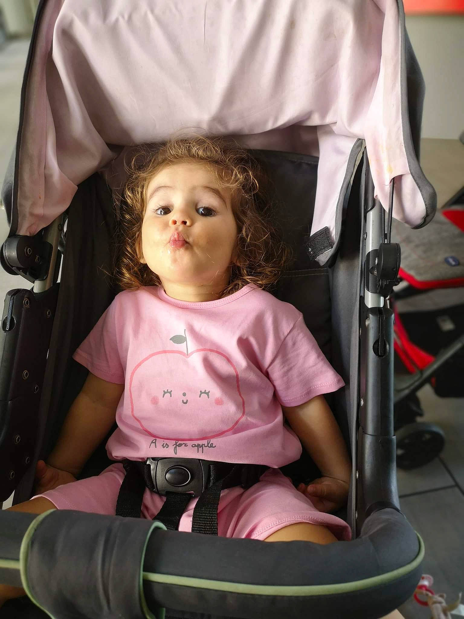 Inaya participe au concours pour gagner de l'argent avec cette photo : baby_carriage, black, cheek, comfort, eye, facial_expression, fun, hair, hairstyle, head, lap, leisure, mouth, organ, person, photograph, pink, product, skin, toddler