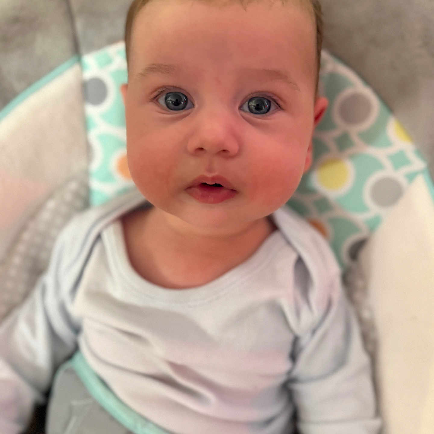 Jaxson is registered to the contest to win money with this photo: baby, child, infant, face, eyes, onesie, seat, patterned, comfort, curious, closeup, rosy_cheeks, soft, looking, expression, indoor, portrait, cute, young, person