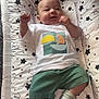 baby, baby_care, background, child, comfort, cushion, cute, face, fists_up, green_shorts, indoor, infant, lying_down, person, portrait, smiling, socks, soft, star_pattern, white_tshirt