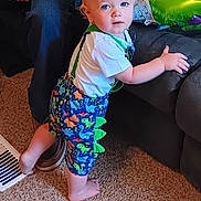 Rhett joined the competition — help win amazing prizes! toddler, child, blue_eyes, dinosaur_shorts, carpet, couch, indoor, person, adult, hand, foot, clothing, standing, home, furniture, colorful, shorts, suspenders, curious, baby