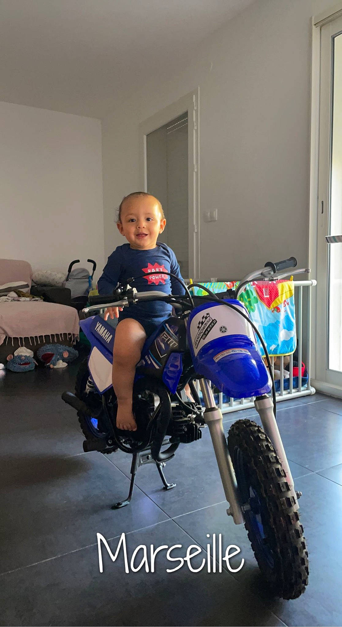 Matia a rejoint le concours — aidez-le/la à gagner de superbes lots ! automotive_design, automotive_lighting, automotive_tire, automotive_wheel_system, bicycle_tire, chair, electric_blue, fender, joy, motor_vehicle, motorcycle, person, rim, smile, spoke, sportswear, t_shirt, tire, toddler, tread