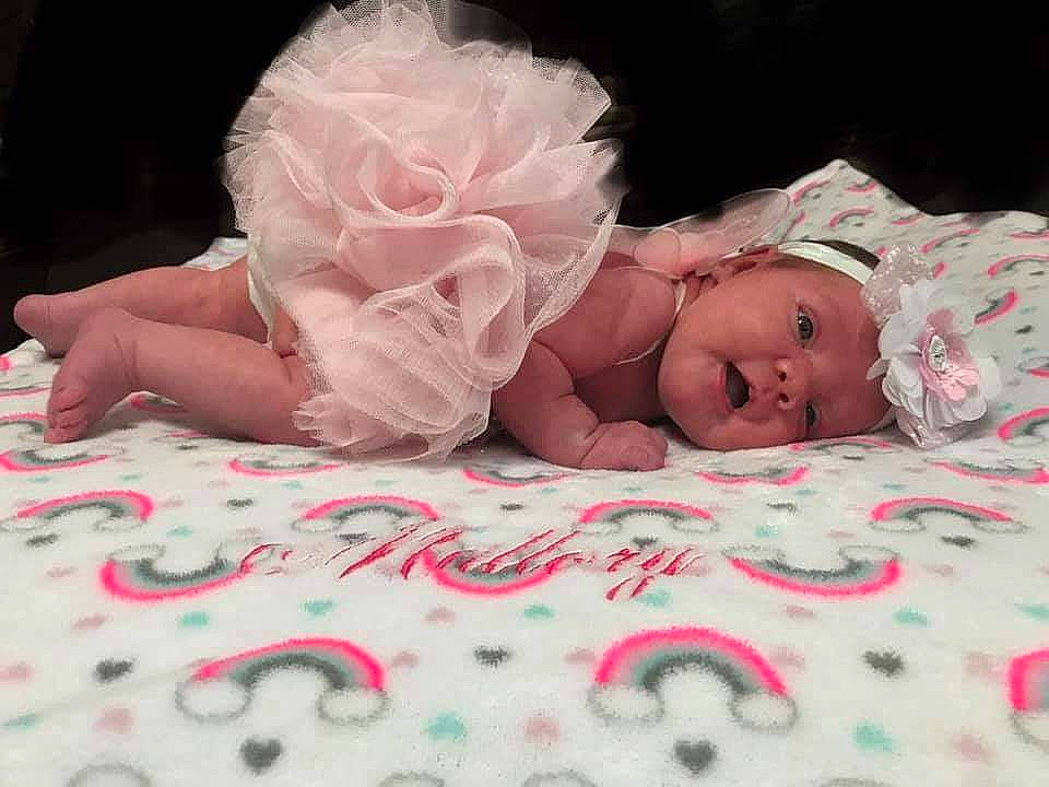 Mallory is registered to the contest to win money with this photo: baby, baby_toddler_clothing, bedding, child, comfort, fashion_accessory, flower, hand, headpiece, headwear, human_body, linens, person, petal, pink, plant, rose, rose_family, rose_order, skin