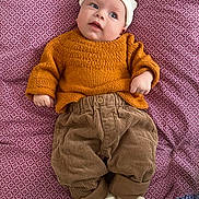 Félix a rejoint le concours — aidez-le/la à gagner de superbes lots ! baby, infant, child, newborn, hat, bear_hat, knitted_sweater, mustard_sweater, corduroy_pants, patterned_sheet, bedding, slippers, plush_slippers, lying_down, portrait, eyes_open, cute, cozy, hand, curious_expression