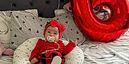 Sofia joined the competition — help win amazing prizes! baby, infant, red_clothing, headband, pacifier, pillow, bed, balloon, number_six, plaid_skirt, stockings, cute, indoors, celebration, decor, child, person, comfort, soft, smiling