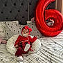 baby, infant, red_clothing, headband, pacifier, pillow, bed, balloon, number_six, plaid_skirt, stockings, cute, indoors, celebration, decor, child, person, comfort, soft, smiling