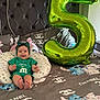 Sofia joined the competition — help win amazing prizes! baby, infant, balloon, number_5, green_clothing, headband, bed, pillow, cartoon_characters, stitch, angel, chanel_logo, smiling, celebration, indoor, footwearless, cute, happy, child, portrait
