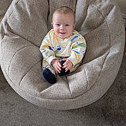 Jax is registered to the contest to win money with this photo: baby, child, smiling, chair, cushion, cozy, indoor, carpet, clothing, socks, face, person, seated, home, comfort, cute, small, infant, relaxed, portrait