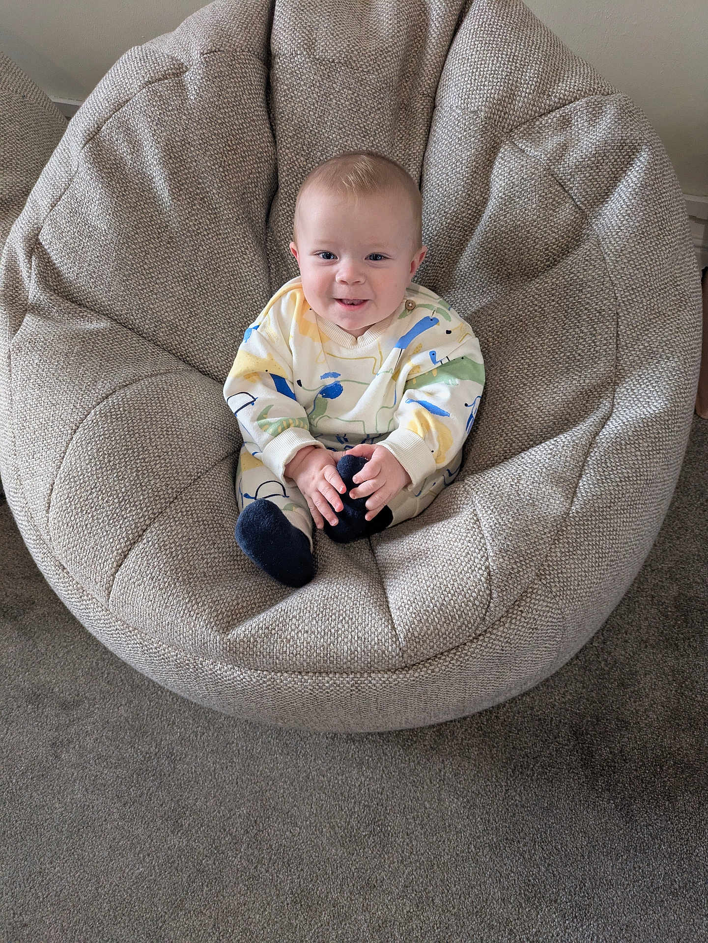 Jax is registered to the contest to win money with this photo: baby, child, smiling, chair, cushion, cozy, indoor, carpet, clothing, socks, face, person, seated, home, comfort, cute, small, infant, relaxed, portrait