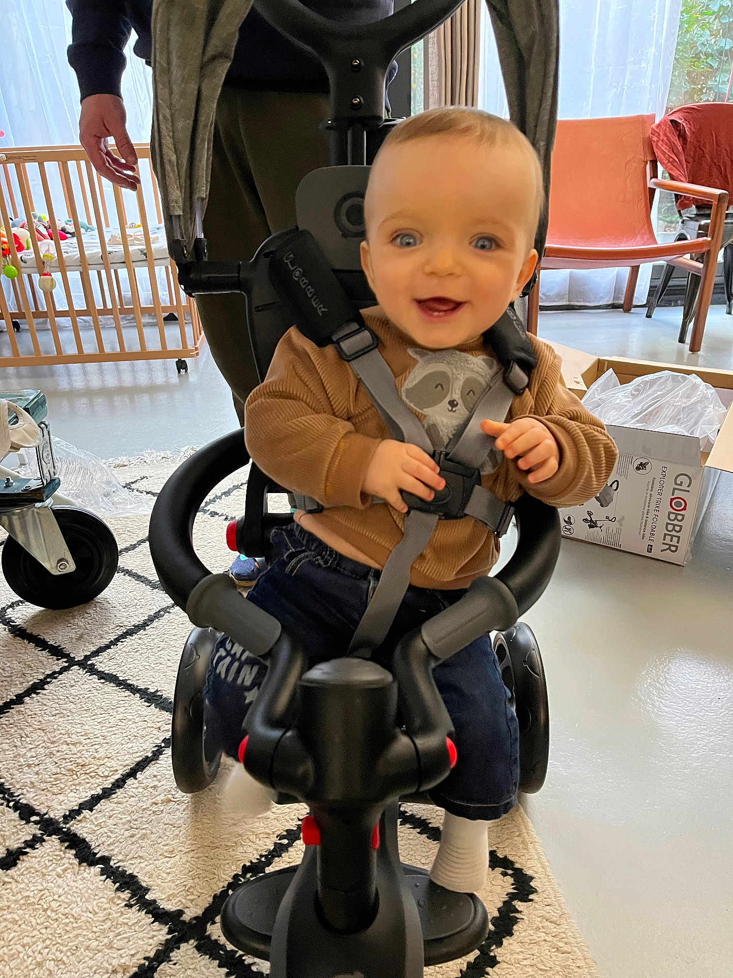 Noé participe au concours pour gagner de l'argent avec cette photo : baby, child, tricycle, smile, indoor, toy, person, seatbelt, carpet, window, chair, box, floor, hand, clothing, sock, furniture, curtain, happy, playtime