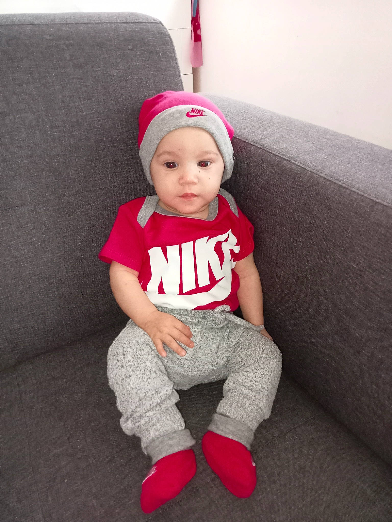 Aaliyah a rejoint le concours — aidez-le/la à gagner de superbes lots ! baby, baby_toddler_clothing, cap, child, costume_hat, couch, eye, hat, head, headwear, human_body, human_leg, knee, leg, living_room, person, sitting, sleeve, sock, t_shirt