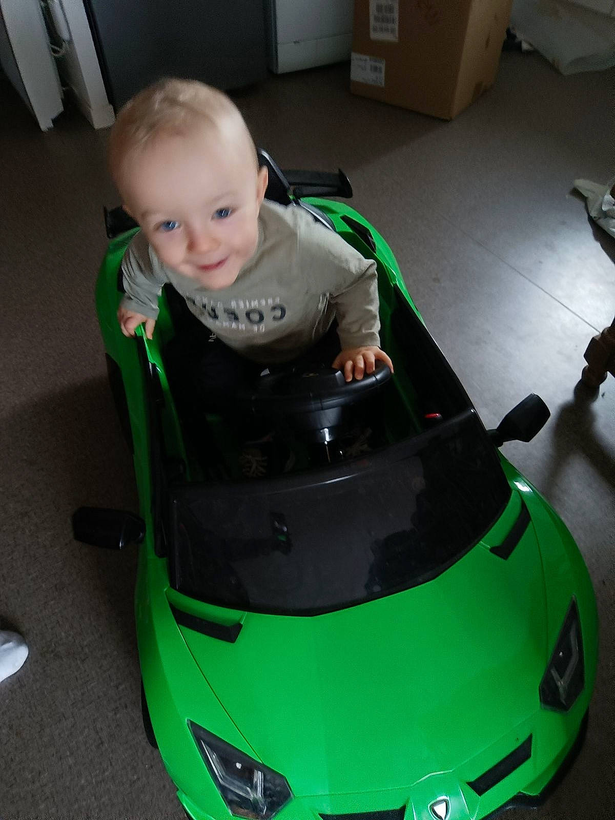 Ayden participe au concours pour gagner de l'argent avec cette photo : automotive_design, automotive_exterior, automotive_fog_light, automotive_lighting, bumper, car, green, grille, headlamp, hood, joy, motor_vehicle, person, personal_luxury_car, riding_toy, smile, tints_and_shades, tire, toddler, vehicle