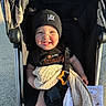 Jax is registered to the contest to win money with this photo: toddler, child, smiling, beanie, stroller, blanket, fabric_book, sunlight, outdoor, happy, clothing, baby, seatbelt, person, cute, daylight, playful, infant, headwear, holding