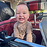 Jax is registered to the contest to win money with this photo: baby, child, smile, happy, outdoor, sunlight, boat, seat, cushion, red, black, clothing, person, face, head, hair, mohawk, blue_sky, metal, strap