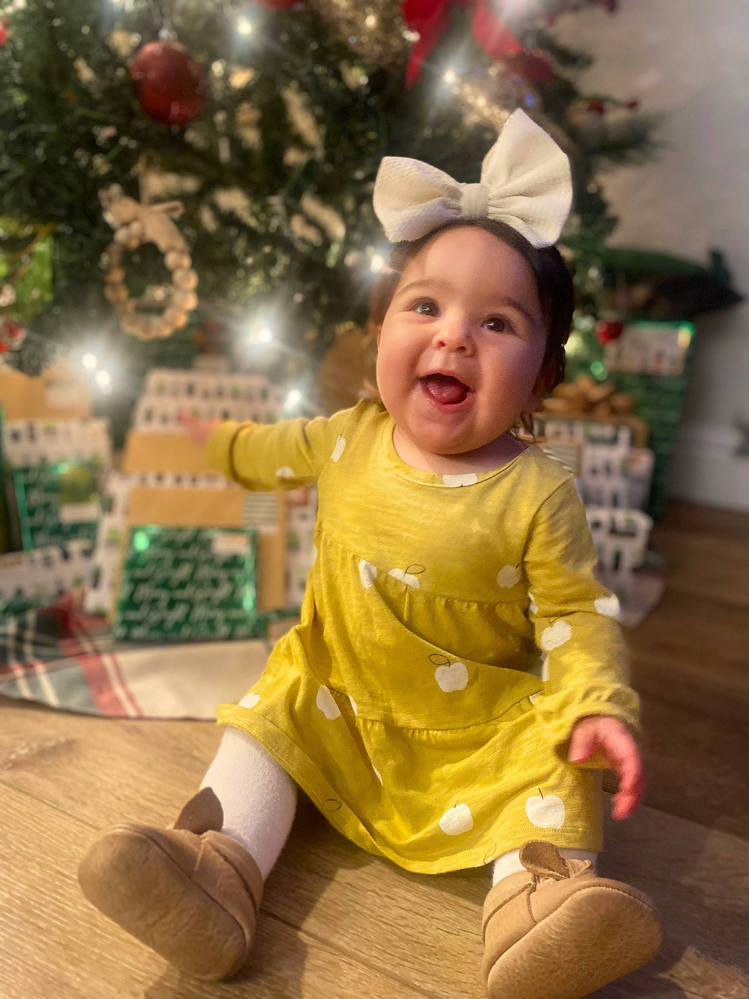 Olive is registered to the contest to win money with this photo: baby, baby_toddler_clothing, child, christmas_decoration, christmas_ornament, christmas_tree, event, face, facial_expression, fun, happy, head, headwear, holiday, human_body, ornament, person, sleeve, smile, standing