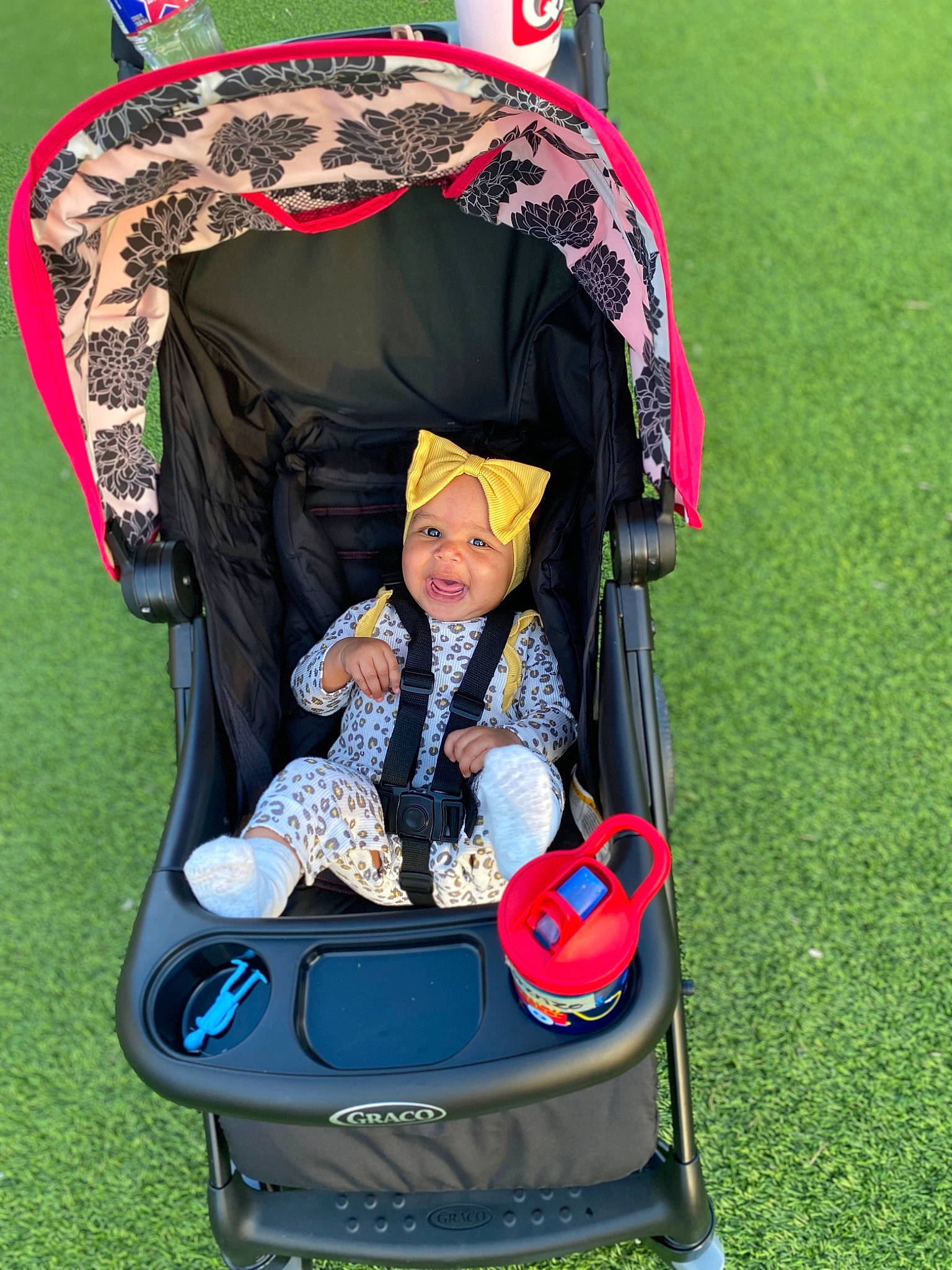 Emilia is registered to the contest to win money with this photo: auto_part, baby, baby_carriage, baby_products, bag, child, event, fashion_accessory, fun, grass, headwear, lap, leisure, magenta, motor_vehicle, person, recreation, sitting, smile, toddler