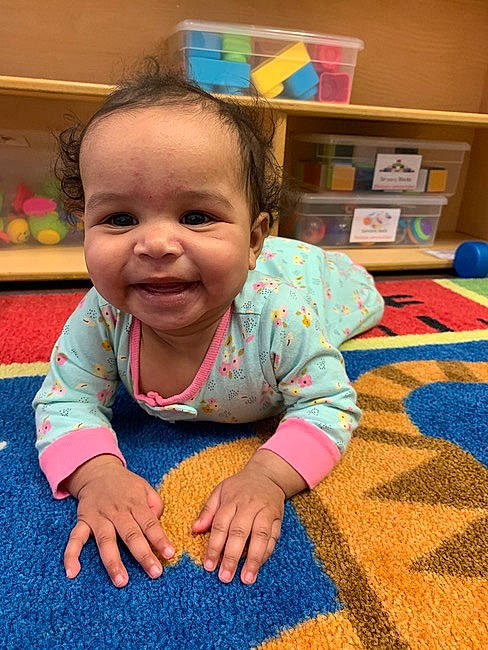 Emilia is registered to the contest to win money with this photo: baby, baby_toddler_clothing, blue, cheek, child, crawling, finger, floor, flooring, fun, happy, joy, leisure, nose, person, play, room, skin, smile, standing